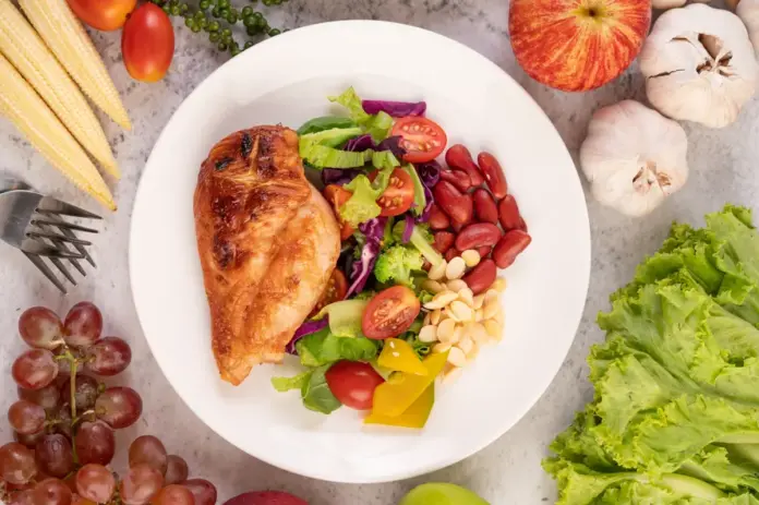 chicken-steak-topped-with-white-sesame-peas-tomatoes-broccoli-pumpkin-white-plate